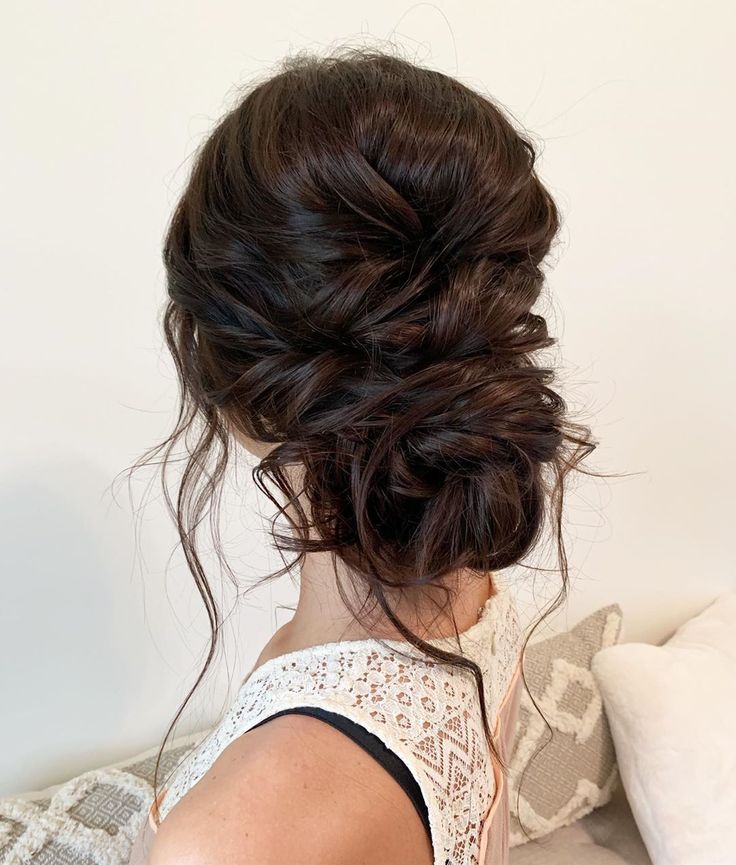 a woman sitting on top of a bed with her hair up in a low bun