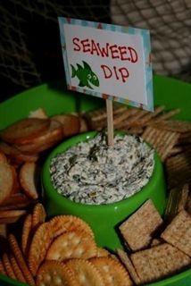 a green plate topped with crackers and a sign that reads, seaweed dip