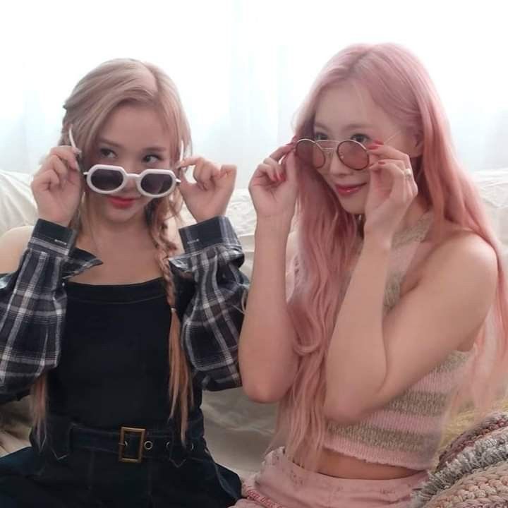 two young women sitting on a couch with their glasses up to their eyeglasses