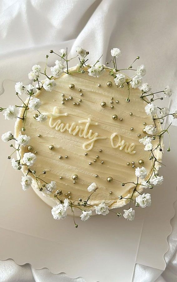 a cake with frosting that says party one surrounded by white flowers and greenery