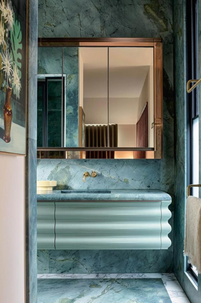 a bathroom with marble counter tops and blue walls