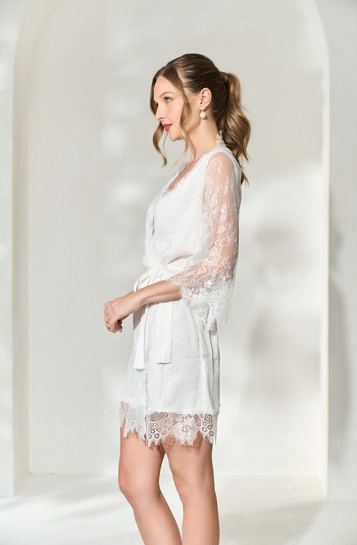 Made in a unique delicate white french lace design, the Lara Lace Robe is the perfect gift for the bride-to-be on her wedding day. Featuring scalloped lace edges along the neckline, hem and sleeve cuffs, this robe exudes old-world elegance. The body of the Lara Robe is fully lined to provide our brides the coverage they need. A slip dress is not required for under this robe, but if you're in search of one we recommend our White Bridal Slip Dress. Material: French lace with a fully lined bodySlee Lace Dress With Lace Cuffs For Wedding Night, Feminine Scalloped Lace For Wedding, Elegant Cotton Lace Top, Feminine White Scalloped Lace, Long Sleeve Lace Wedding Dress With Lace Cuffs, White Scalloped Lace Dress For Wedding Night, White Lace Dress With Lace Bodice For Ceremonies, Elegant Lace Trim Dress For Ceremony, Elegant Lace Dress With Scalloped Lace For Wedding Night