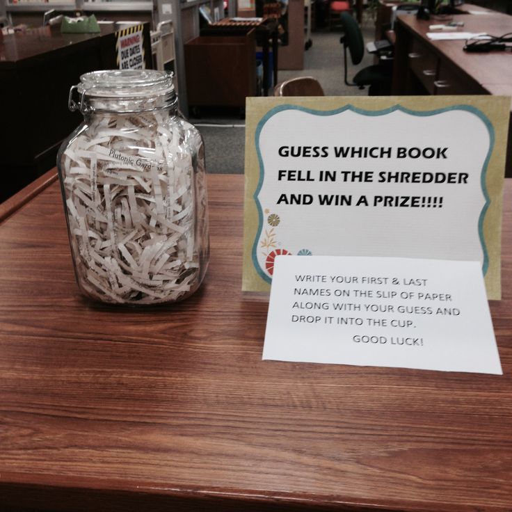 a glass jar filled with white shredded paper sitting on top of a wooden table next to a sign