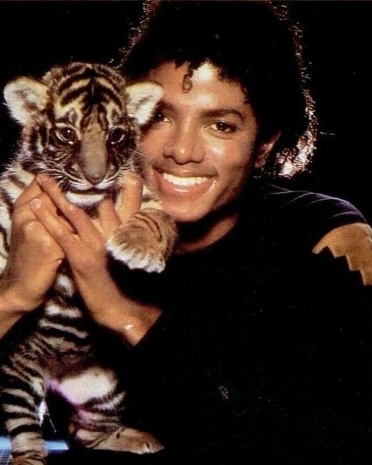 a woman holding a small tiger cub in her hands