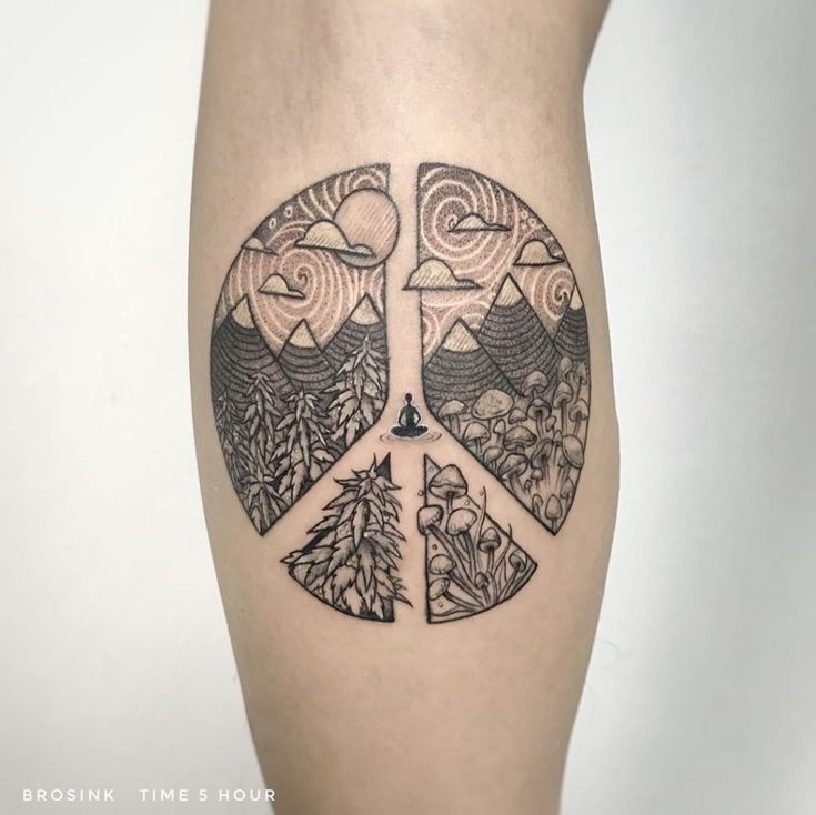 a black and white photo of a peace sign tattoo on the right thigh, with mountains in the background