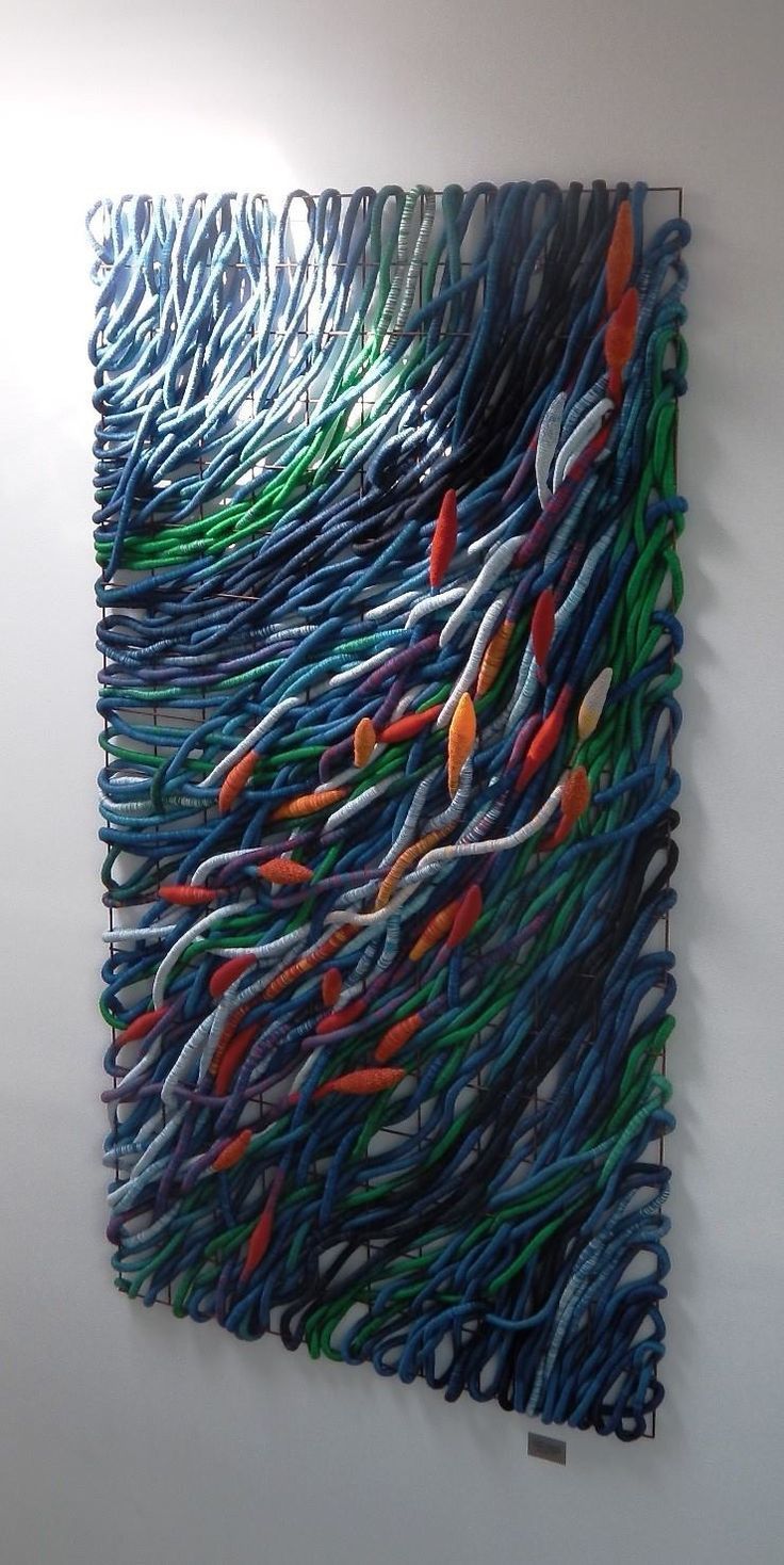 an art piece made out of many different colored wires on a wall in a room