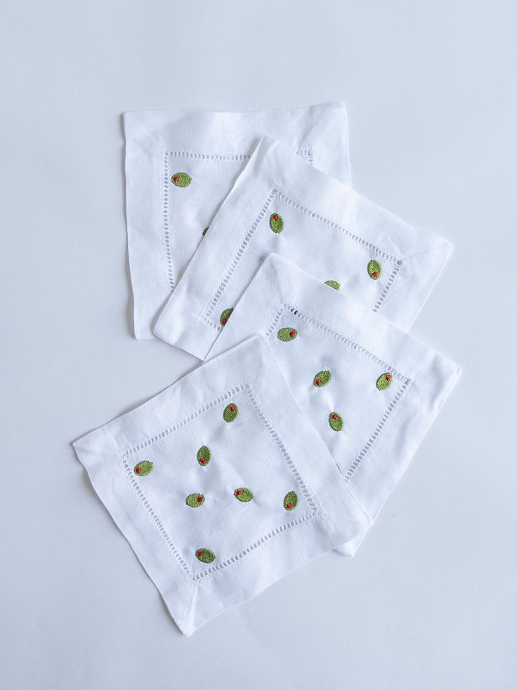 four white napkins with green leaves on them