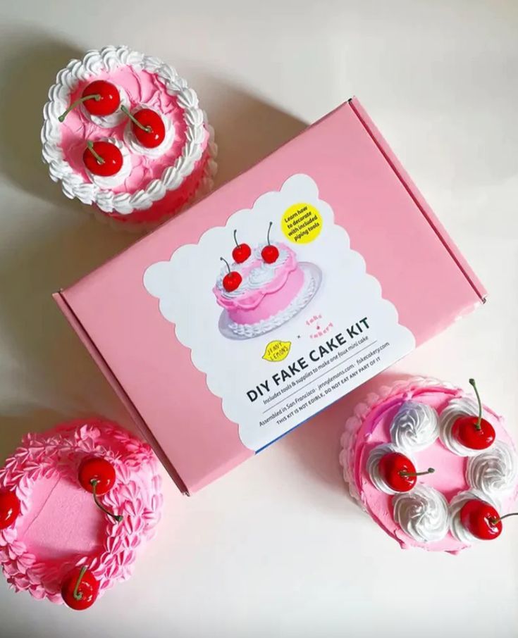 two pink cakes with cherries on top in a box