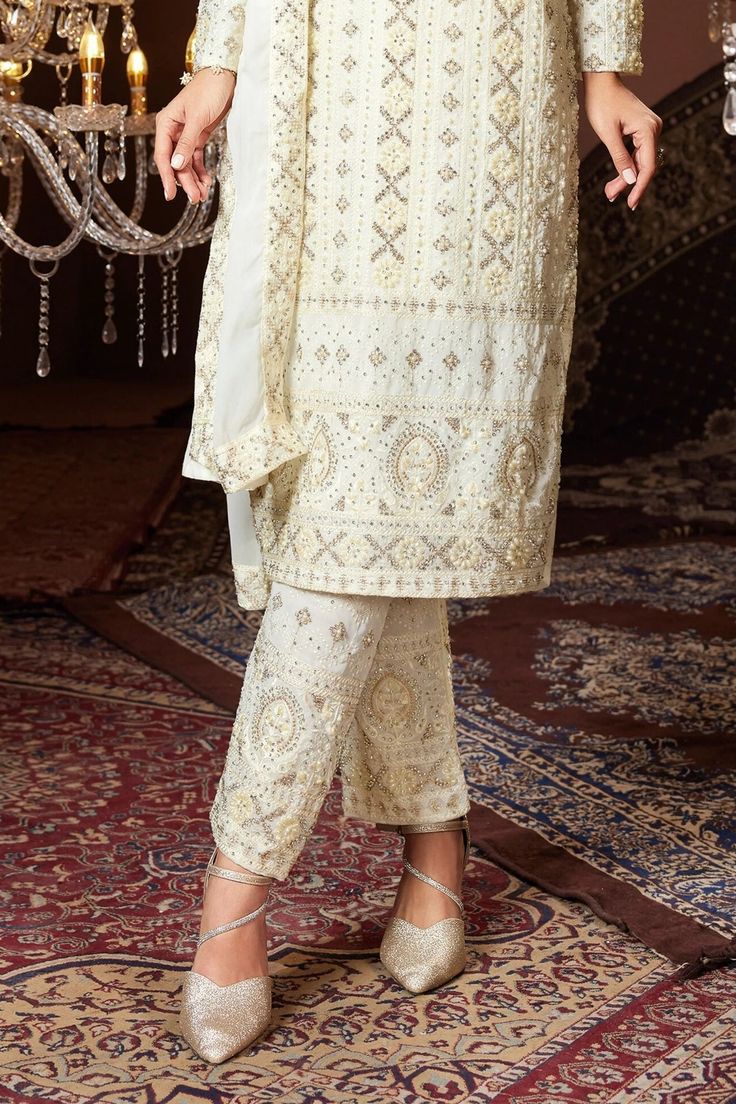 This Ivory Georgette Heavy Embroidered Pant Style Suit boasts an elaborate all-over embroidery pattern with delicate stone and pearl detailing. It is complete with coordinating ankle length pants and a dupatta for a polished and sophisticated appearance. This suit is essential for any special event. Color: Ivory Fabric: georgette Work: handwork, stone, sequins, pearls, thread work Kameez length: 42" Bottom length: 41" Sleeve length: 16" Kameez with side zipper Side slit Lined Round neck Inside m Phulkari Pants, Lucknowi Kurta, Gharara Suits, Patiala Salwar Suits, Bridal Dupatta, Phulkari Dupatta, Chikankari Suits, Plus Size Suits, Sharara Suit