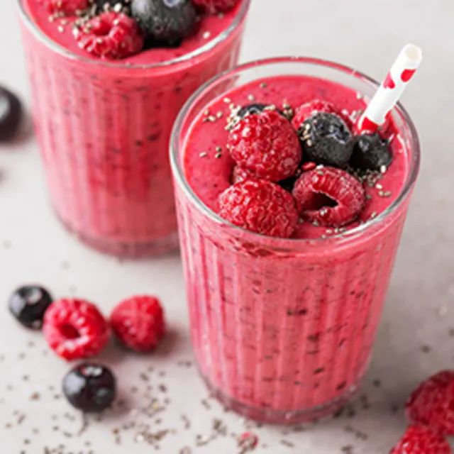 two glasses filled with raspberry smoothie and berries