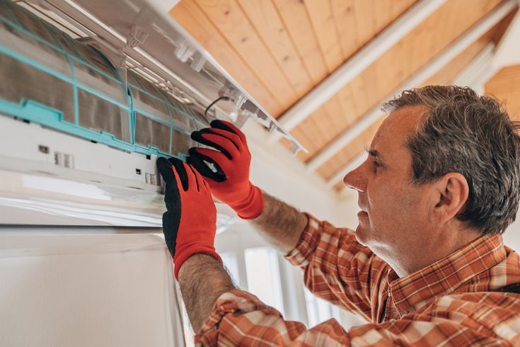 a man working on an appliance in the kitchen with gloves and work gloves