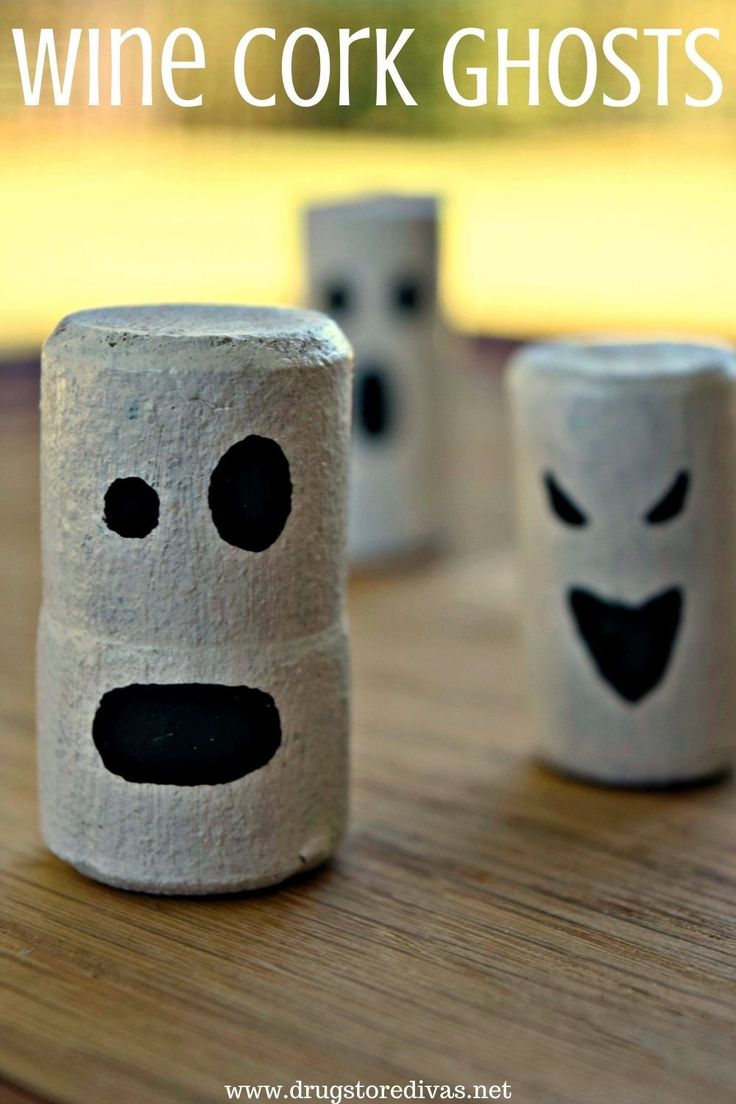 three toilet paper rolls with faces painted on them and the words wine cork ghost written in white