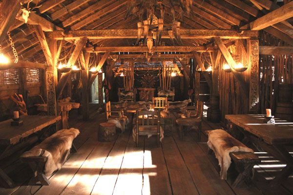 the inside of a restaurant with wooden tables and benches covered in cow hides,