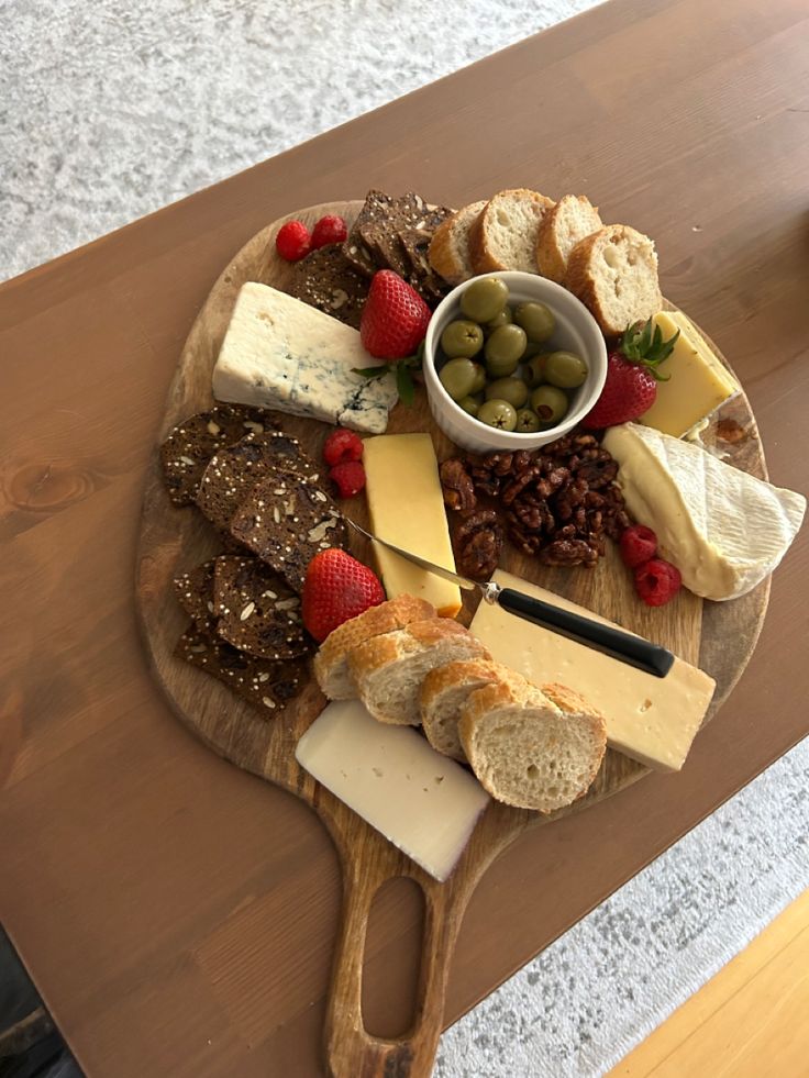 an assortment of cheeses and bread on a wooden platter