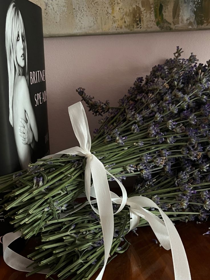 a bouquet of lavenders and a book are on a table next to each other