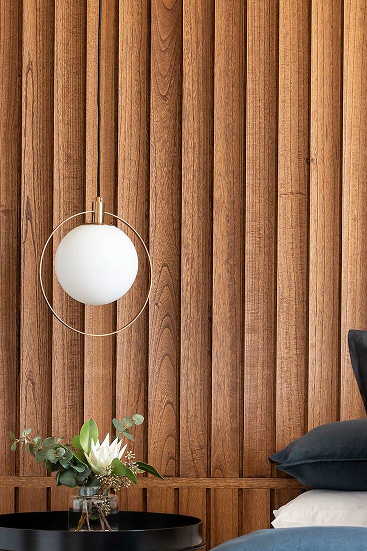 a bedroom with wood paneling and a round lamp hanging from the ceiling next to a bed