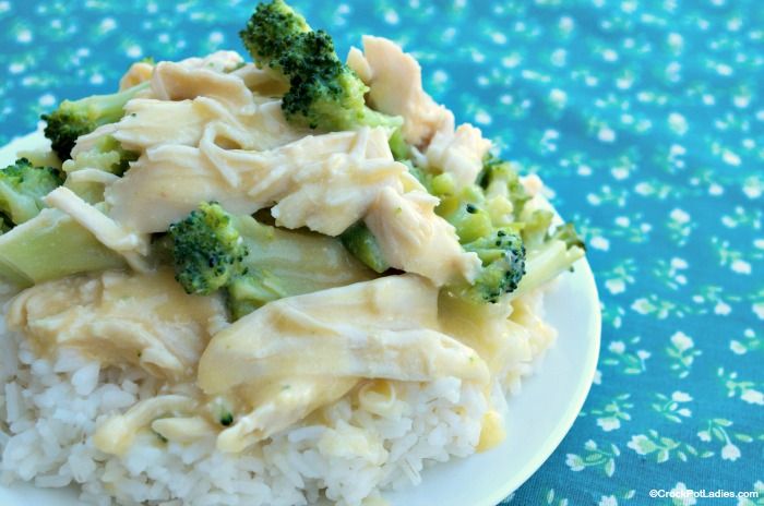 a white plate topped with rice and broccoli covered in cheese sauce on top of a blue tablecloth