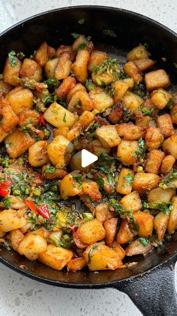 a pan filled with potatoes and vegetables on top of a stove