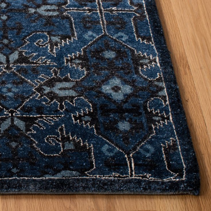 a blue area rug with an intricate design on the top and bottom, sitting on a wooden floor