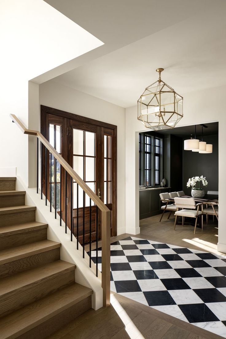 a staircase leading up to a living room with black and white checkered flooring