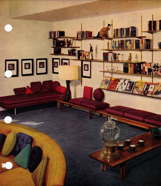 a living room filled with purple couches and lots of books on the shelves above them