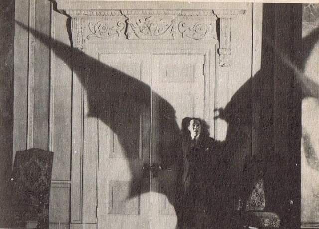 black and white photograph of a woman standing in front of a door with her arms outstretched