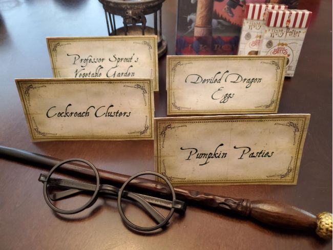 three harry potter business cards and two reading glasses on a table next to a wand