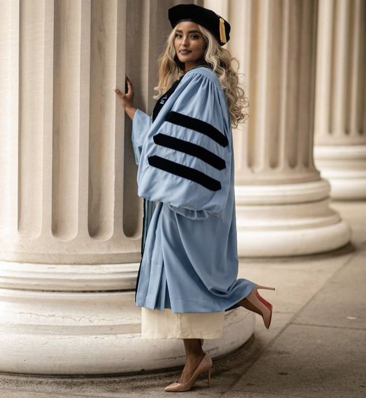 a woman in a graduation gown leaning against a column