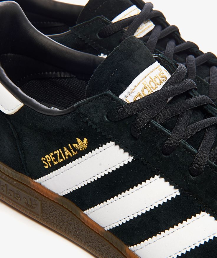 a black and white adidas sneakers with gold lettering on the soles is shown