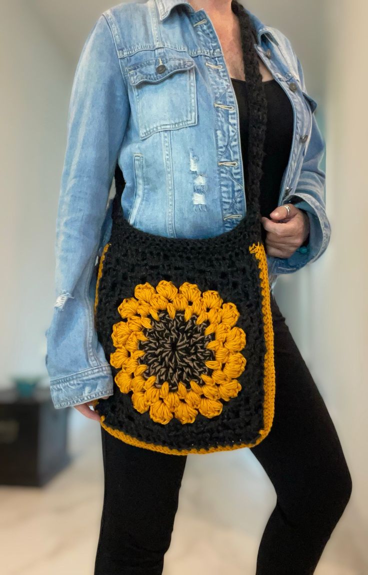 a woman is holding a crocheted bag with a sunflower design on it