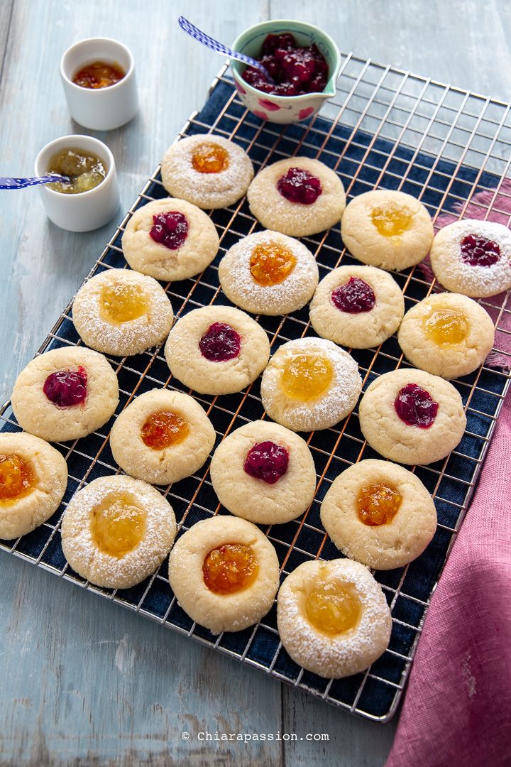 small cookies with jams and jelly on a cooling rack next to bowls of condiments