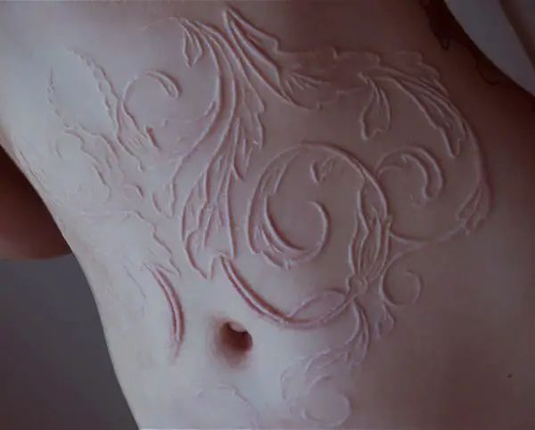 a close up of a woman's stomach with intricate designs on the side and breast