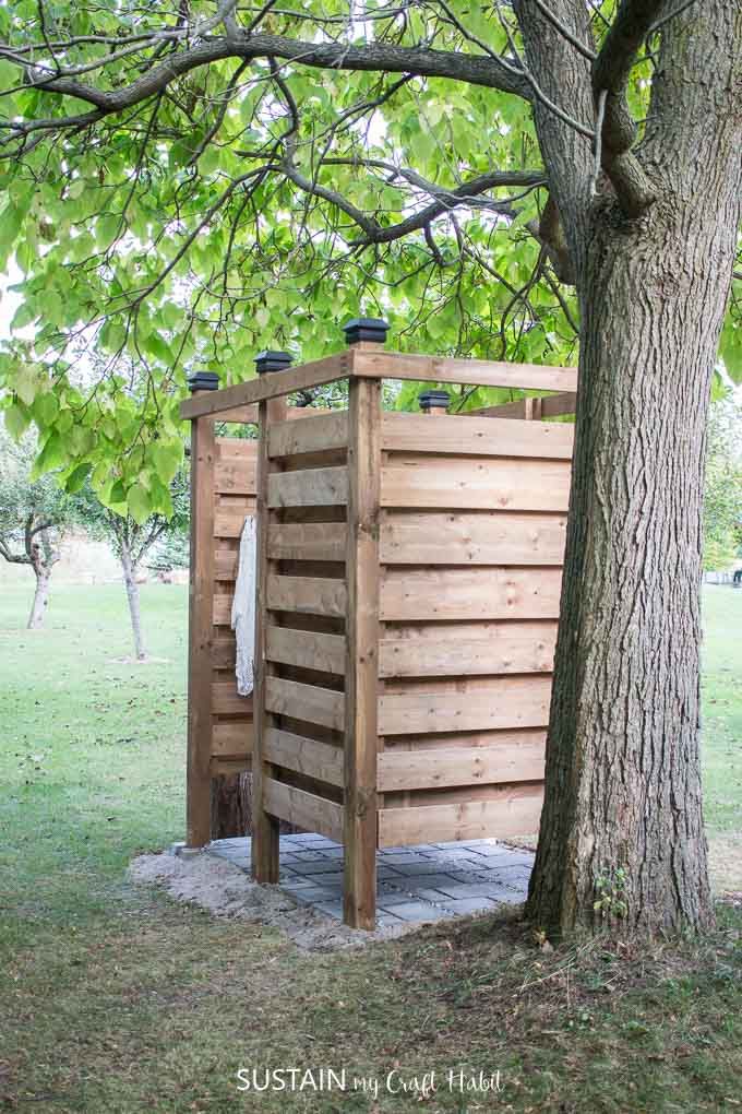 a wooden outhouse next to a tree