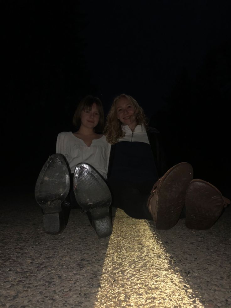 two women sitting on the ground at night