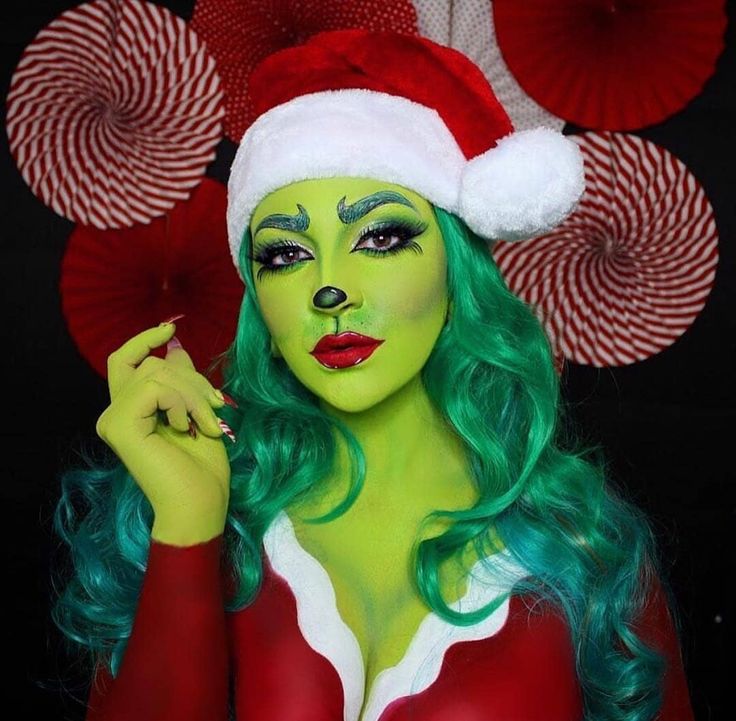 a woman with green hair wearing a santa claus hat and holding her hand up to her face