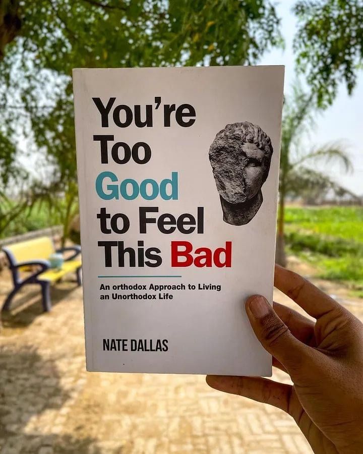 a person holding up a book with the title you're too good to feel this bad