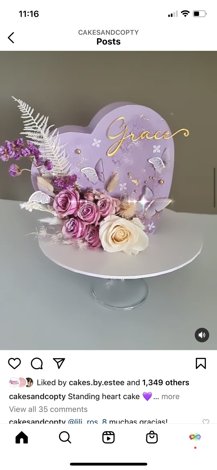 the cake is decorated with purple flowers and gold lettering on it's heart shaped stand