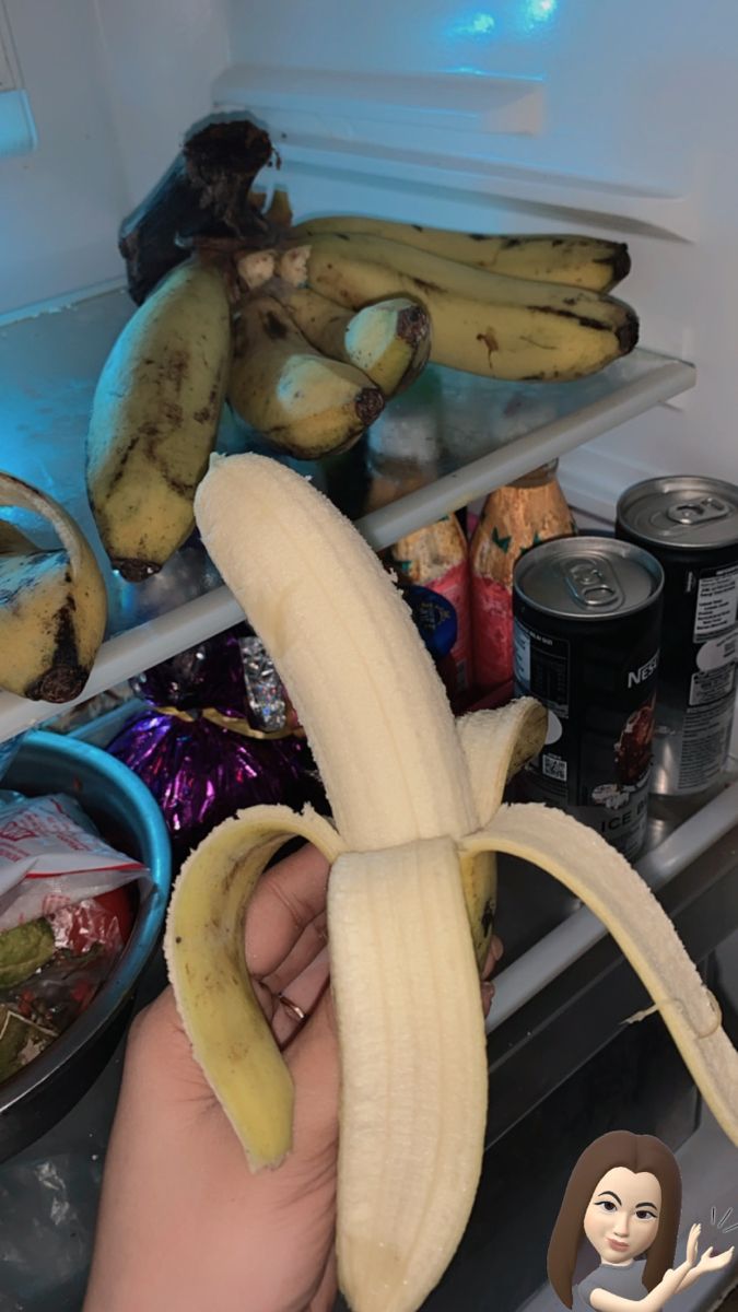 a person holding a banana in front of an open refrigerator