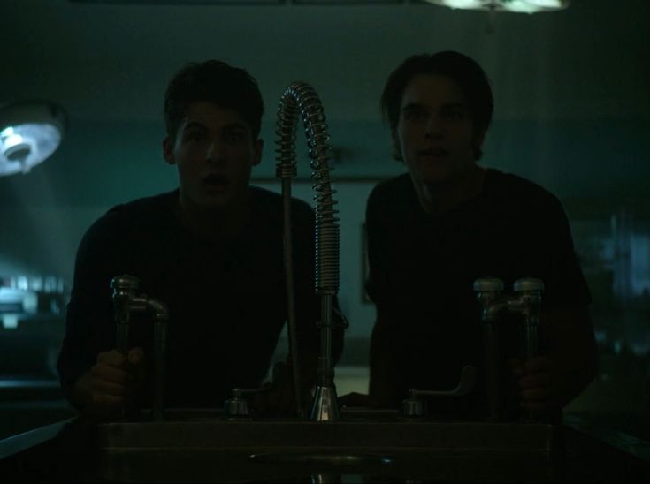 two young men sitting at a sink in a dark room