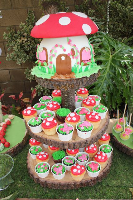 a table topped with cupcakes covered in green frosting and mushroom shaped decorations