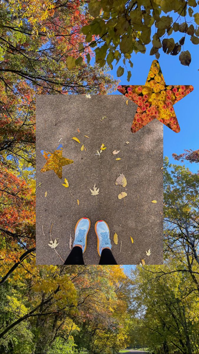 someone's feet are standing on the ground in front of trees with leaves falling from them