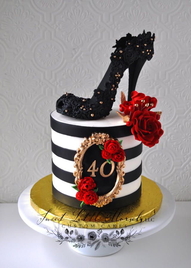 a black and white striped cake with red roses on the top, high heeled shoe