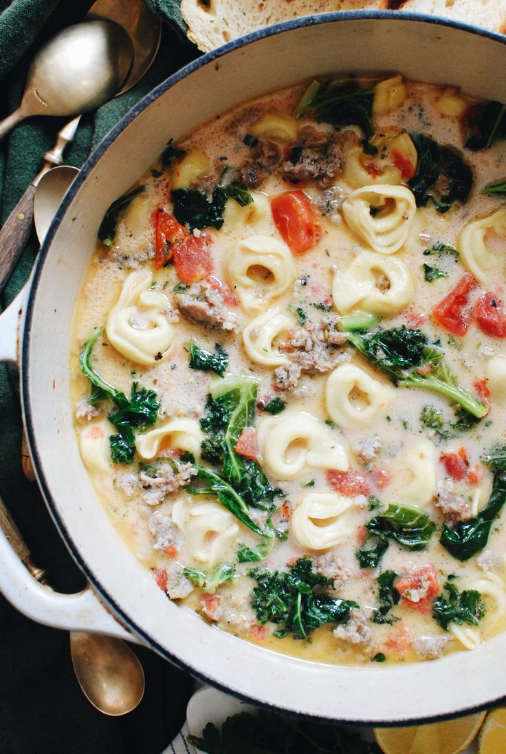 a pot filled with pasta and spinach on top of a table