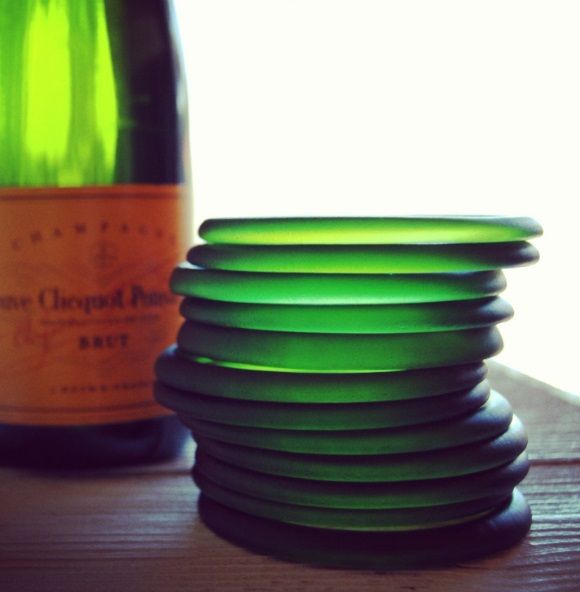 a stack of green plates next to a bottle of wine