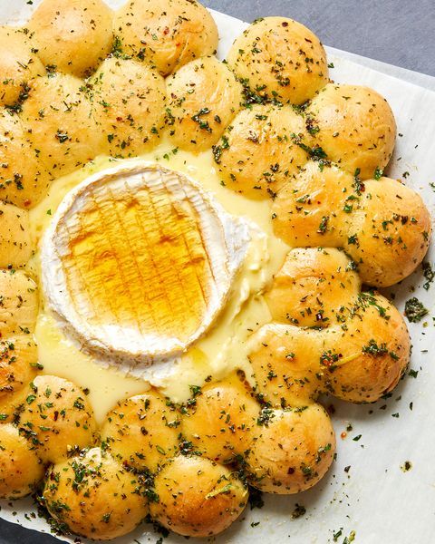 a platter filled with rolls covered in cheese and topped with a buttery dip