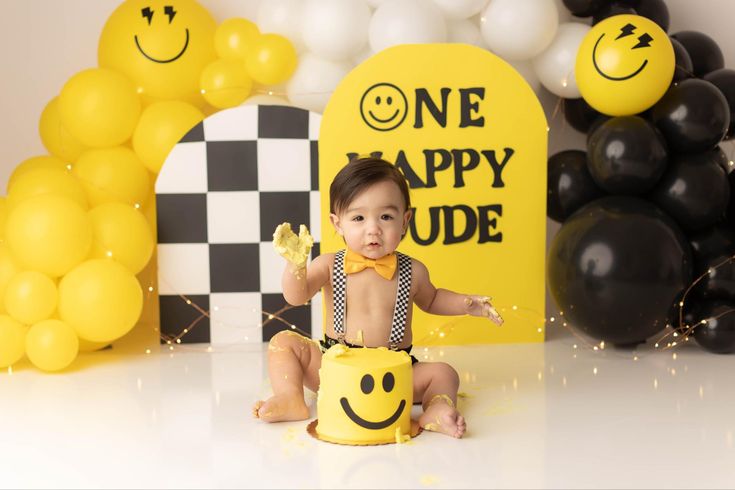 a baby sitting on the floor in front of some balloons