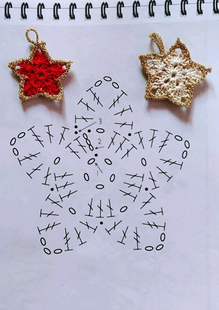 two gold and red ornaments sitting on top of a white sheet of paper next to each other