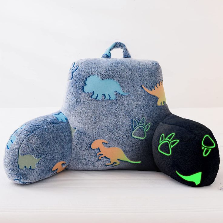 a stuffed animal with dinosaur designs on it's back and its pillow in the shape of a backpack