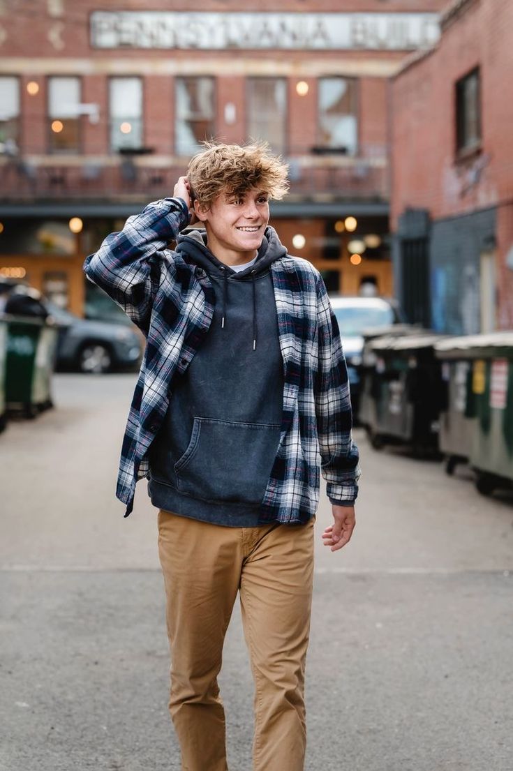 a young man is walking down the street with his hand on his head and smiling