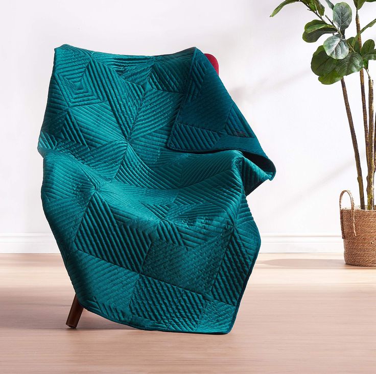 a green chair sitting on top of a wooden floor next to a potted plant